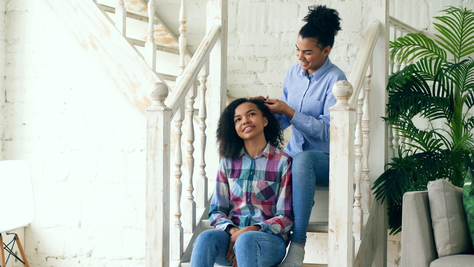 Mother styling her daughter's hair on stairs.